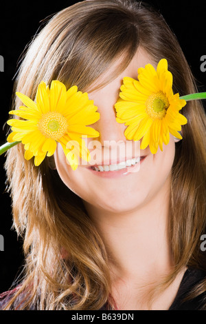 Teenager-Mädchen für ihre Augen mit Blumen Stockfoto