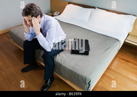 Geschäftsmann, sitzen auf dem Bett und leiden unter Kopfschmerzen Stockfoto
