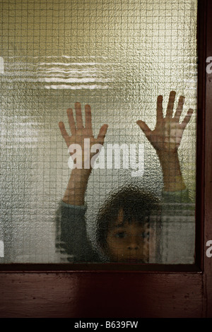 Sechs Jahre alter Junge hinter Glas Stockfoto