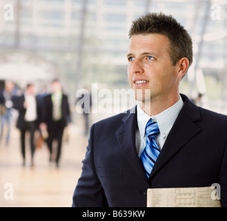 Porträt von glücklich erfolgreicher Geschäftsmann hält lächelnd Zeitung Stockfoto