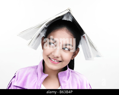 asiatische Mädchen indischer Herkunft mit einem Buch auf dem Kopf Stockfoto