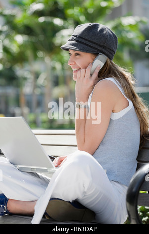 Junge Frau telefonieren mit einem Handy und einen Laptop verwenden Stockfoto