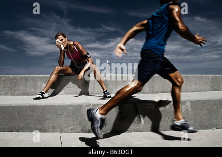 Männlicher Athlet läuft mit einer Sportlerin ruht auf Schritte und ihr Gesicht abwischen Stockfoto