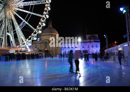 Nachtaufnahme von zwei Freunden zusammen Eislaufen im Winter-Wunderland-Eisbahn in Cardiff, Wales. Rücken-Tropfen enthält Rathaus Stockfoto