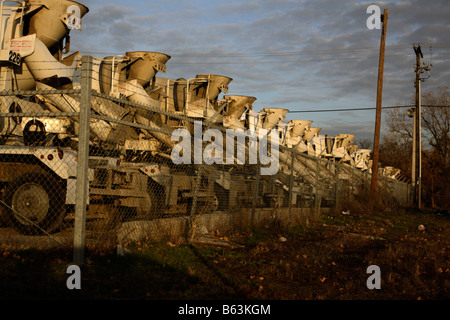 Reihe von Betonmischer-LKW in einer Linie von der untergehenden Sonne beleuchtet. Stockfoto