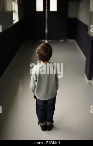 Sechs Jahre alter Junge steht allein in Schule Flur Stockfoto