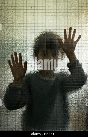 Sechs Jahre alter Junge hinter Glas Stockfoto
