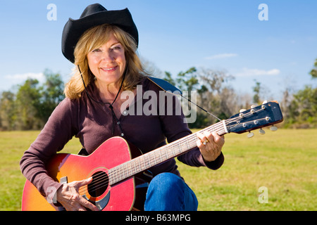 Schöne Reife Frau spielt Country western Musik auf der Gitarre Stockfoto