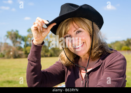 Schöne Reife Frau kippen ihren Cowboy-Hut auf einem Bauernhof Stockfoto