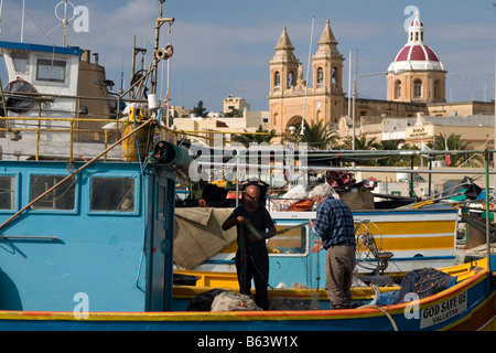 Die Fischer Netze in ihrer traditionellen Fischerboot in Marsaxlokk, Malta zu sortieren. Stockfoto