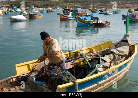 Fischer Netz in seiner traditionellen Fischerboot in Marsaxlokk, Malta zu sortieren. Stockfoto