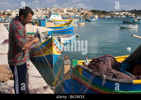 Fischer Netz in seiner traditionellen Fischerboot in Marsaxlokk, Malta zu sortieren. Stockfoto