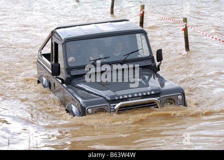 Grüne kurzer Radstand Land Rover Defender mit anti-Roll-Bar im Wasser bei Abrechnung herumfahren 4WD Allradantrieb LRM zeigen Stockfoto