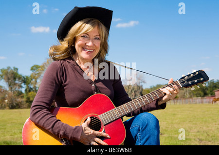 Schöne Reife Cowgirl spielt Country-Musik auf dem Bauernhof Stockfoto