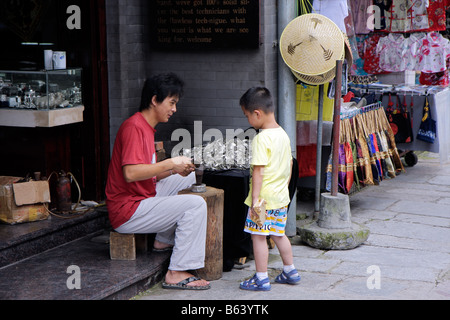 Chinesischer Mann und junge, die Herstellung von Schmuck vor seinem Strassenlokal, Yangshuo, China Stockfoto