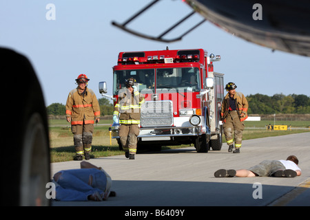 EMS und Feuerwehrmann Personal sind eingetroffen, um den Menschen helfen und bewerten den verletzten unter einem Flugzeug auf einem Flughafen in Wisconsin Stockfoto