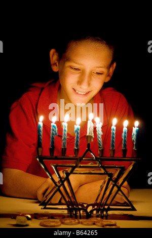 Kleiner Junge am beleuchteten Menorah beleuchtet nur durch seine leichte geringe Schärfentiefe mit Fokus auf junge s Augen blickte Stockfoto