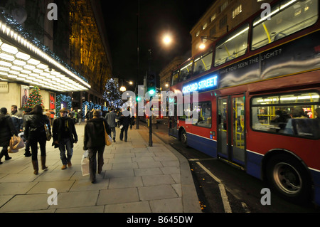 Oxford Street Weihnachten Dekorationen Bus mit beleuchteten Werbetafel und Käufer außerhalb Selfridges Haupteingang Stockfoto