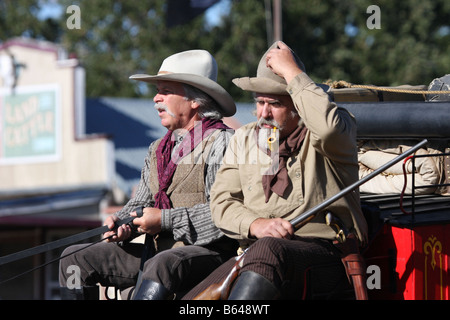 Zwei Cowboys der Postkutsche durch eine alte Westernstadt fahren Stockfoto