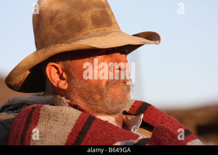 Ein Oldtimer Cowboy lehnte sich gegen seinen Pack und Sattel bei Sonnenuntergang Stockfoto