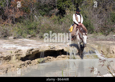 Ein Cowboy und Pferd überquert einen Fluss in Texas Stockfoto