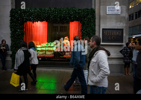 Weihnachts-Einkäufer gehen vorbei an Santa Claus in einem saisonalen Fenster des Kaufhauses Selfridges in der Oxford Street Stockfoto