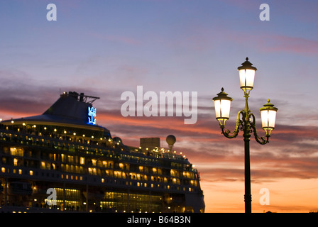 Straßenlaterne bei Sonnenuntergang mit Kreuzfahrt Schiff vorbei durch im Canale di San Marco, Sestiere Castello Venedig Italien Stockfoto