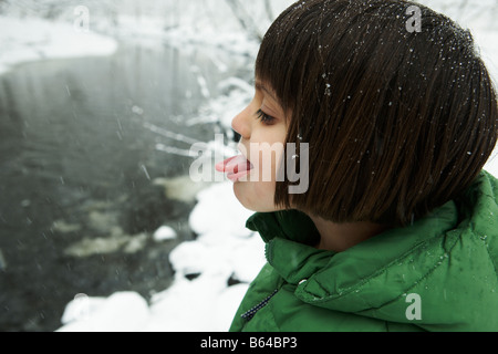 5 Jahre altes Mädchen ihre Zunge Schneeflocken zu fangen Stockfoto