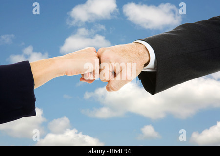 Weibliche und männliche Geschäft Hände tun eine Faust stoßen mit Himmel als Hintergrund Stockfoto