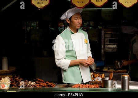 Kreditor Koch Grill verkaufen gegrilltem Fleisch und Fisch am Imbissstand in Shanghai s Old Street in der ehemaligen Stadt Gottes Tempel Stockfoto