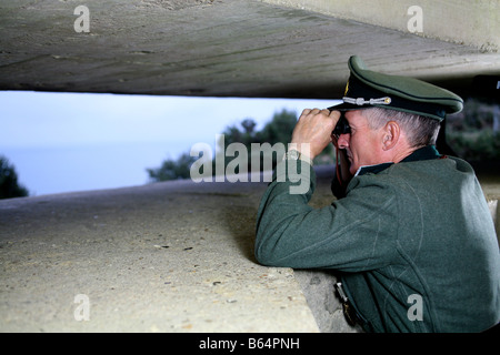 Ein Schauspieler verkleidet als ein deutscher Offizier, Blick über den Ärmelkanal von einem deutschen D-Day-Bunker in der Normandie Frankreich Stockfoto