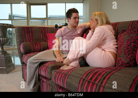 ein Liebespaar, das sitzen auf einem Sofa umarmten einander und liebevoll miteinander zu reden entspannt Stockfoto