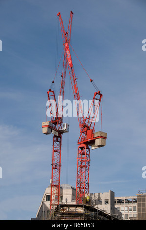 Zwei rote Kräne gegen blauen Himmel mit weißen Wolken Stockfoto