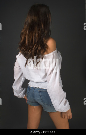 High-Fashion Porträt einer jungen, gebräunte, Brünette, shorts Teen Mädchen trägt einen losen weißen Hemd und kurze Jeans. Stockfoto