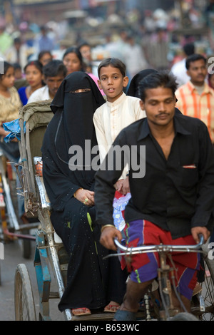 Indien, Uttar Pradesh, Varanasi, Straßenszene. Verschleierte Moslim Frau und Sohn in Fahrradrikscha oder Pedicap. Stockfoto