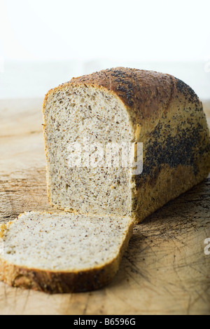 Laib Brot, eine Scheibe ruht auf Schneidebrett Stockfoto