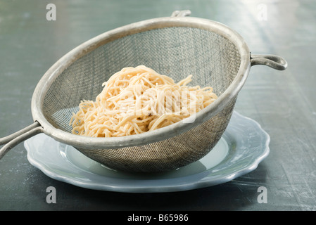 Spaghetti in Metall Sieb ruht auf Platte Stockfoto