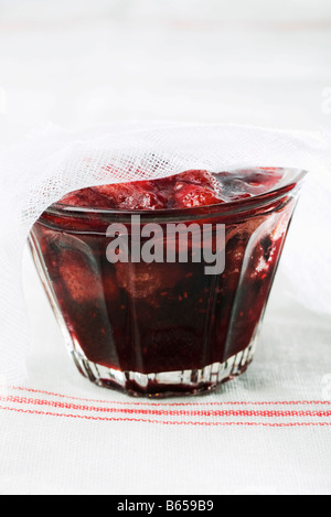 Glas mit Erdbeermarmelade, die teilweise durch Gaze abgedeckt Stockfoto