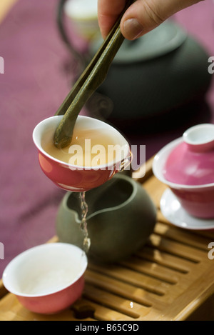 Teetasse mit Tee-Zange, erste Gebräu in Teetablett ausgießen statt Stockfoto