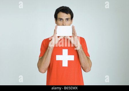Mann mit Schweizer Flagge t-Shirt, leere Karte vor Mund halten Stockfoto