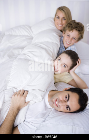 Familie zusammen im Bett liegend, in die Kamera Lächeln Stockfoto