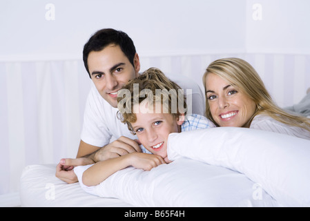 Eltern und Sohn auf Bett, lächelnd in die Kamera, Porträt Stockfoto