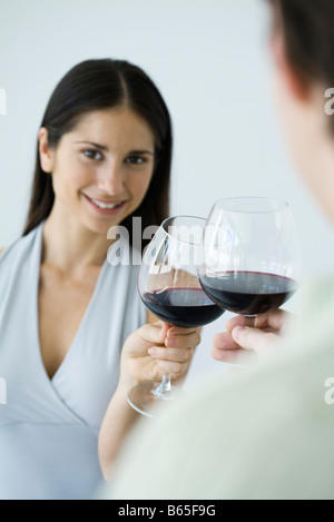 Paar klirrende Gläser Rotwein, Frau lächelt in die Kamera, beschnitten Ansicht Stockfoto