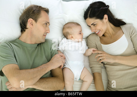 Familie ruht auf Bett, Baby lag zwischen Eltern, Draufsicht Stockfoto