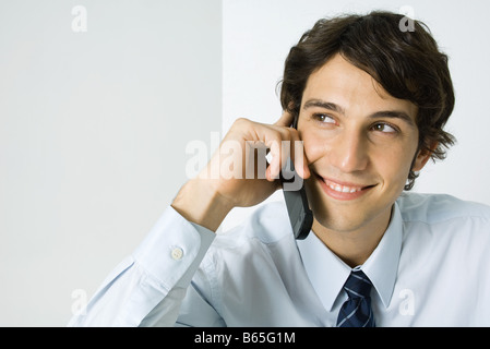 Junger Mann mit Handy, wegsehen, Lächeln Stockfoto