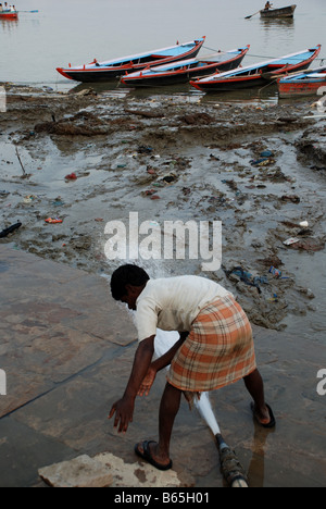 Mann mit Wasserstrahl vom Fluss Ganges. Varanasi, Indien. Stockfoto