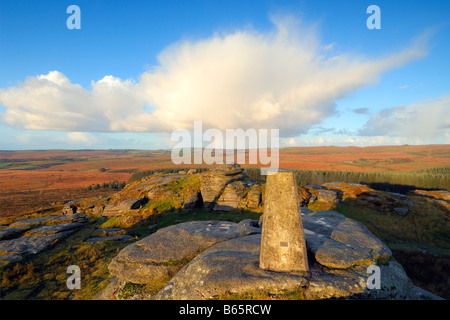 Licht des frühen Morgens und ein Regenbogen am Bellever Tor auf Dartmoor in South Devon UK mit der Triangulation Säule auf dem Gipfel Stockfoto