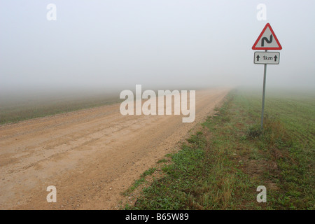 Kurvenreiche Straße Zeichen im Nebel. Stockfoto