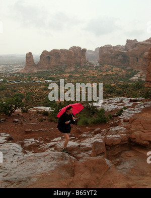 Mädchen mit roten Regenschirm vor den Garten Eden Felsformationen, Arches-Nationalpark Stockfoto