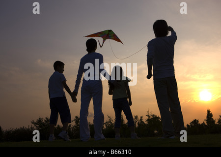 Familie mit zwei Kindern einen Drachen bei Sonnenuntergang Stockfoto